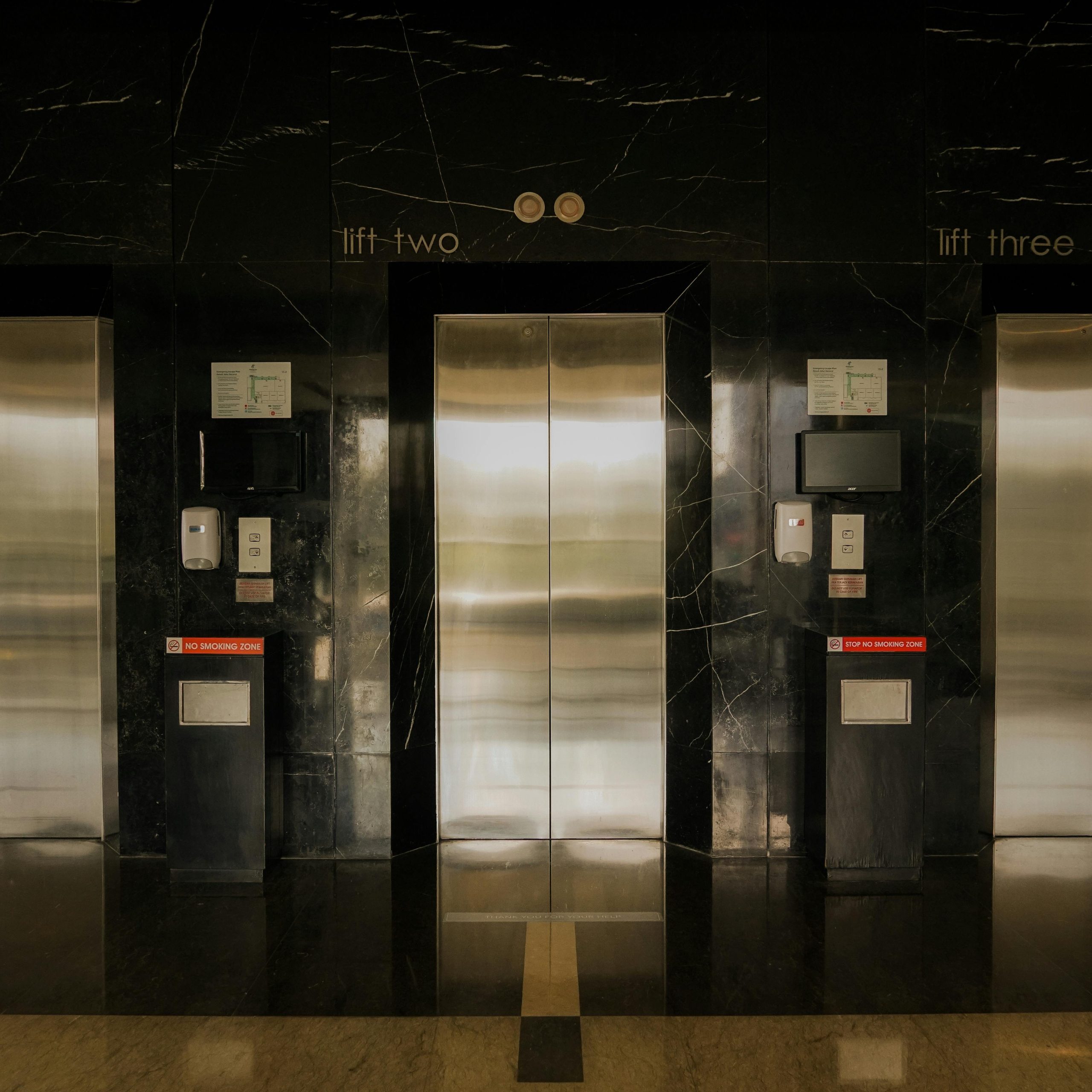 Sleek elevator lobby with stainless steel doors, reflecting modern architecture.