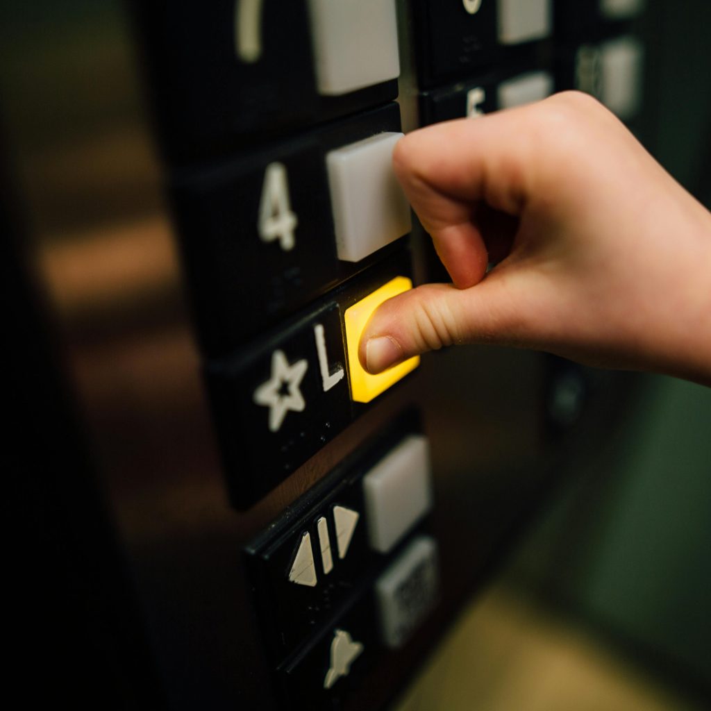 pexels-photo-3861787-3861787 A close-up shot of a hand pushing the 'L' button in an elevator, indoors.