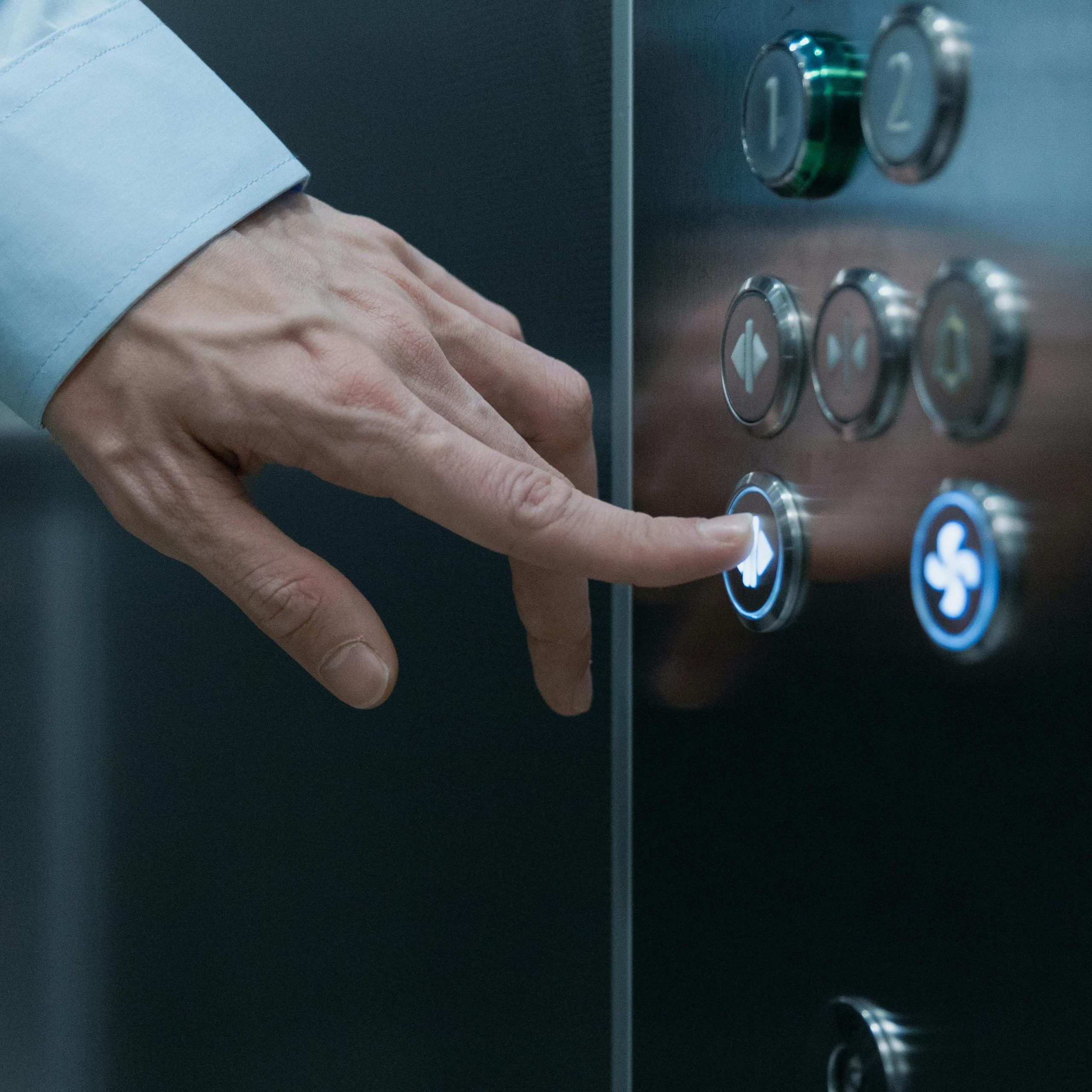 A person pressing an elevator button in a modern building, highlighting technology and urban life.